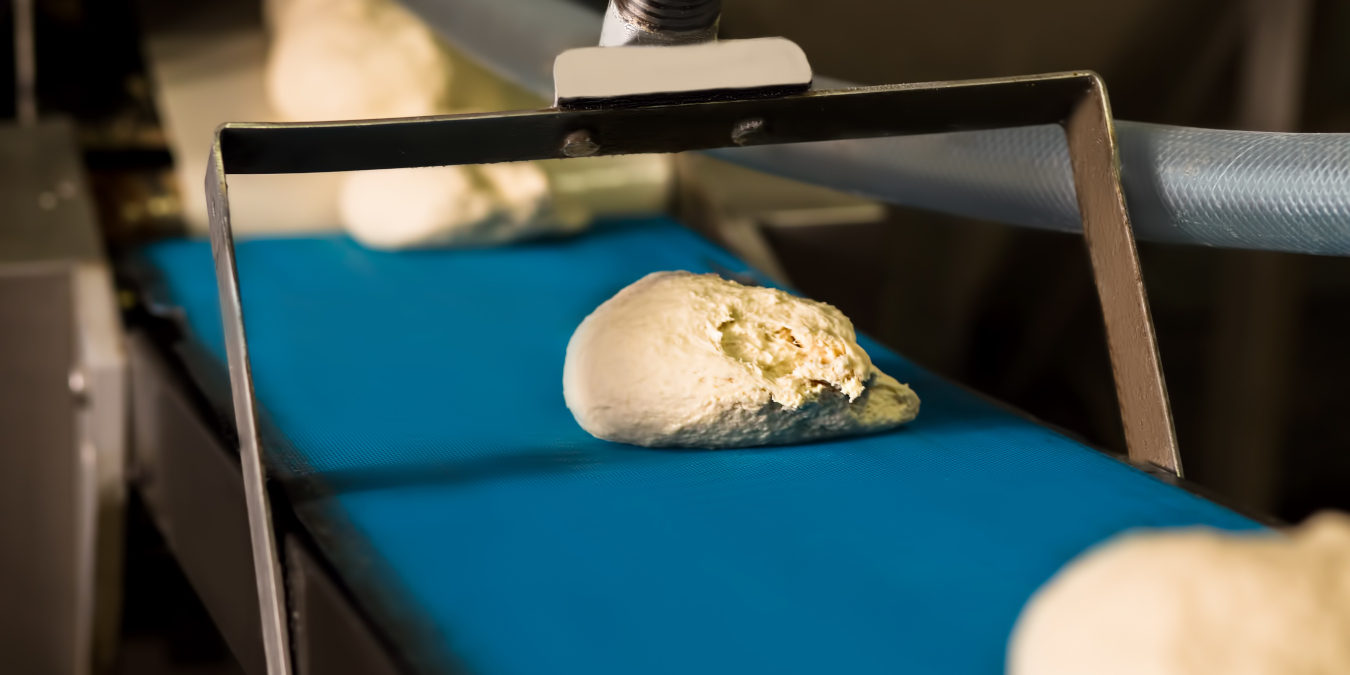 Raw dough on an industrial conveyor belt.