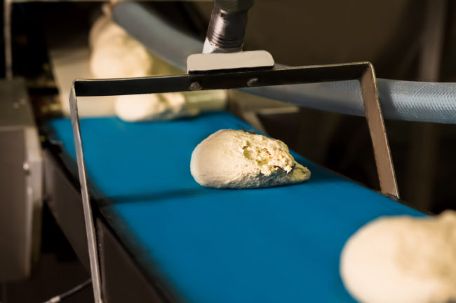 Raw dough on an industrial conveyor belt.