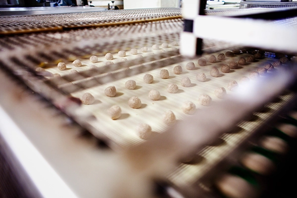 Balls of fresh dough move down an assembly line