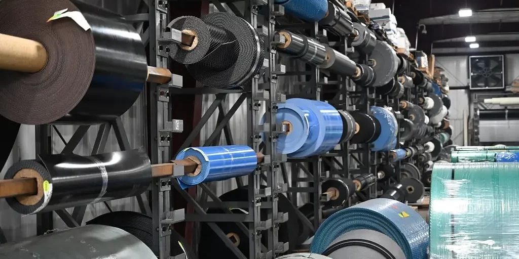 A wall lined with racks of rolled conveyor belt materials.