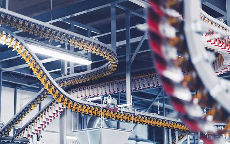 Freshly printed newspapers and magazines being transported by an array of conveyor belts inside a printing facility. Fast moving conveyor belts with belt clamps used to hold and separate the freshly printed paper. Printing press in mass scale.