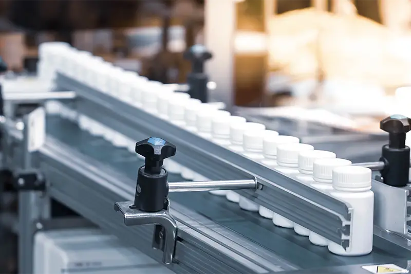 Bottles of medical pill after filling and capping on conveyor. Pharmaceutical industry.